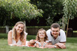 © Andriy Medvediuk - father, mother and two children, baby girl and little daughter on the grass on summer day. Happy family sitting together outdoors, having fun. Happiness and harmony in family life.
