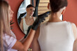 © insta_photos - Female barber holding hair clipper shaving head of young woman reflecting looking in mirror. Brave cancer survivor patient doing new bald hairstyle losing hair becoming hairless after chemotherapy.
