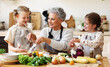 Mature woman with grandchildren preparing healthy food in kitchen