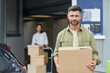 © Seventyfour - Waist up portrait of handsome man holding box and looking at camera while standing by self storage facility, copy space