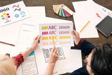 Poster - Hands of mature female designer pointing at paper with letters and words