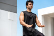 © Atstock Productions - Handsome Indian man doing high knee tap exercise outdoors on building rooftop, open air home workout concept