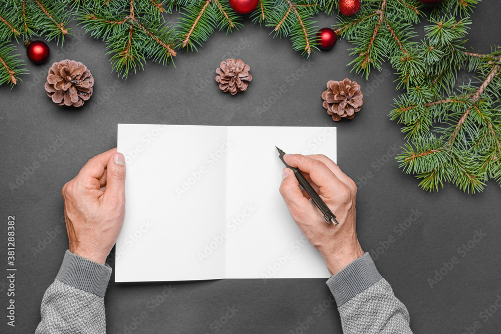 Male hands with blank card and Christmas decorations on dark background