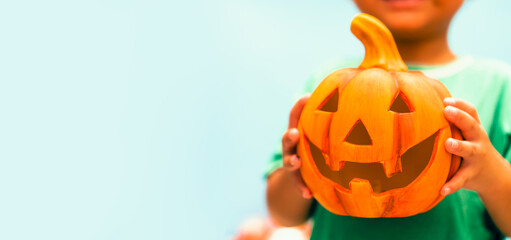 Toddler kid hands holding jack-o-lantern bucket ready for halloween. Children with candy bucket on blue background.Child having fun at Halloween trick or treat.Kids trick or treating.Autumn October