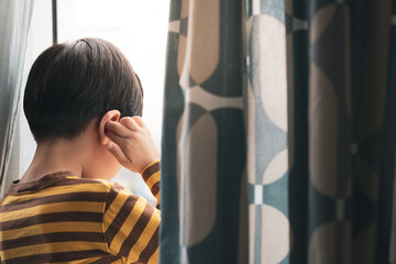 Portrait of a little cute Asian kid hold the colorful puzzles pieces to cover his face. World autism awareness day, Mental health care, Child development, Autism Spectrum Disorder concept.