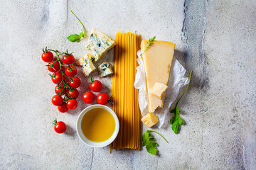 Wall Mural - Cooking pasta background. Raw ingredients for pasta with tomato sauce and cheese on gray background.