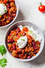 Wall Mural - Chili con carne with rice in gray bowl, top view. Beef stew with beans in tomato sauce with sour cream and rice. Traditional Mexican food concept.