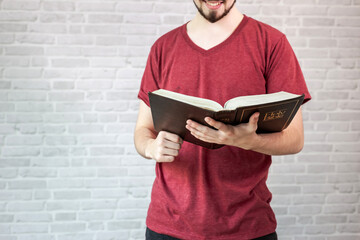 Young man wear a red shirt holding a bible.