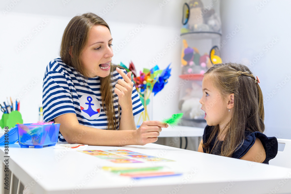 Children speech therapy concept. Preschooler practicing correct pronunciation with a female speech therapist. - obrazy, fototapety, plakaty 