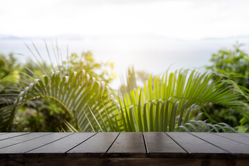 Wall Mural - Wood table top (Bar) with blur on green palm leaves or tree in tropical forest with sky and sea at background