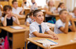 © elenbessonova - Happy kids writing test in elementary school classroom. Schooling