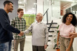 © Svitlana - Cheerful young team greeting new worker in the modern office, Aged man or senior intern shaking hands with his colleagues