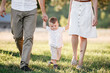 © Andriy Medvediuk - View on toddler. Mother, father hold hands son walk in the park. Young family spending time together on vacation, outdoors. The concept of family summer holiday. selective focus