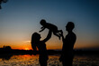 © Andriy Medvediuk - Family walking down the river near the water. Family silhuetts on sunset. Happy family on the lake.