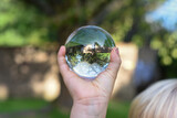 Fototapeta Pokój dzieciecy - a boy holds a glass ball with reflection of a tree as an environmental conservation concept