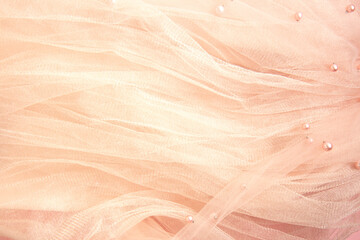 Beautiful nude pink tulle with shiny beads background. Draped background of pink powdery fabric, texture. Copy space
