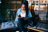 Fototapeta Przestrzenne - Serious African American woman taking note in diary