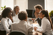 Funny business meeting in office. Office workers confer at their desks and smile. High quality photo.