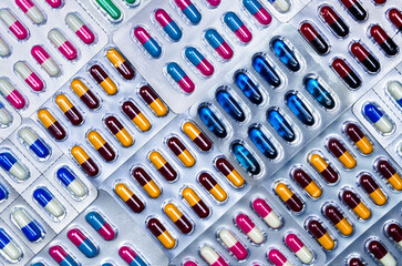 Wall Mural - Top view of capsule pills in blister pack. Pharmaceutical industry. Pharmaceutical manufacturing industry concept. Capsule pills production. Full frame shot of blue, pink, yellow, red, black capsules.