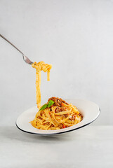 Wall Mural - Eating pasta. Egg pasta tagliatelle with bolognese sauce made from meat and tomato sauce. Traditional italian dish from Bologna. Dynamic photo. Minimalism. Light grey background. Copy space.