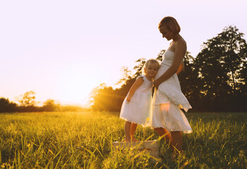 Wall Mural - Young pregnant mother and daughter on nature outdoors.