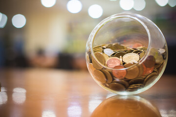 Money coins Thai baht in a round glass jar with Bokeh background. Banking, Finance and Saving money concept.