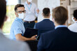 © Drazen - Happy entrepreneur with face mask attending business seminar in board room.