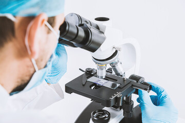 Poster - scientist looks through a microscope in a laboratory. medical and pharmaceutical concept. laboratory