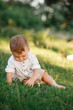 © Andriy Medvediuk - Happy adorable baby boy sitting on the grass in the park on summer day. Child in trendy and cute clothes