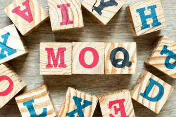 Alphabet letter block in word MOQ (Abbreviation of Minimum Order Quantity) with another on wood background