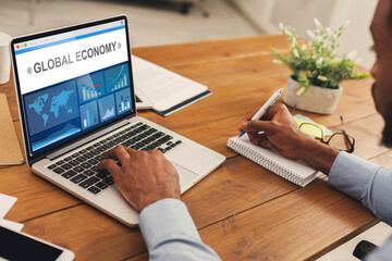 Poster - African Business Man At Laptop Analyzing Economics Graphs In Office