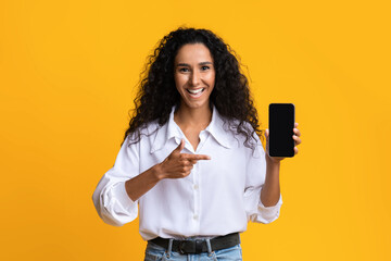 Joyful Brunette Lady Pointing At Smartphone With Black Blank Screen, Mockup