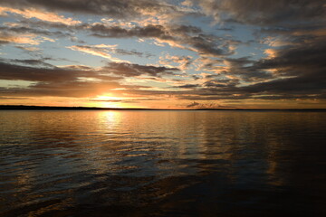 Wall Mural - Shadows and sunlight of sunset on lake water in sky reflection