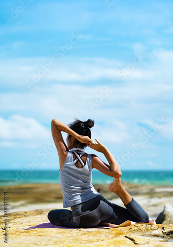 Fotografía A beautiful woman doing yoga on the rocks at the beachside.