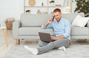 Wall Mural - Freelance man sitting on floor using phone and pc