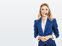 Call Center. Smiling Female Support Phone Operator In Blue Confident Suit And Headset, Isolated Over Grey Background. Caucasian Blond Model In Customer Service Help Consulting Concept.