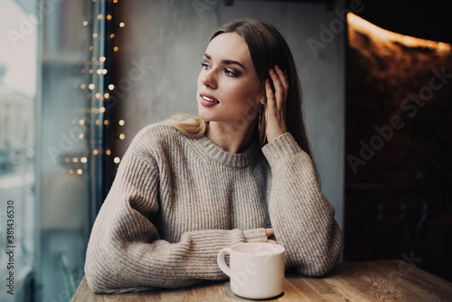 Thoughtful young female drinking tea in modern cafe