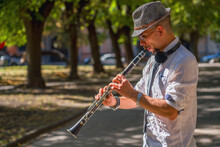 Young Man Playing Clarinet On Walking Street. Street Musician.  Music, Art, Creativity Concept.