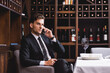 © LIGHTFIELD STUDIOS - Selective focus of man in suit talking on smartphone near glass of wine on table in restaurant