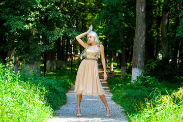 Young beautiful blonde girl in beige dress, summer park outdoor