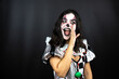 woman in a halloween clown costume over isolated black background telling a secret