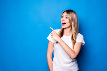 Young Woman Pointing Finger To The Side Over Isolated Blue Background
