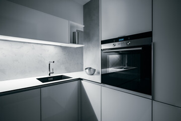 Modern white kitchen corner in minimalist design, during night, with light strip turned on, modern oven, granite sink, and premium materials such as glass, concrete, aluminum and stainless steel.