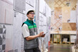 © Roman - caucasian warehouse worker is checking his list on clipboard in warehouse, transportation logistics by trucks. wholesale, logistics, export concept