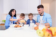 © gorynvd - Happy family with two sons eating healthy morning breakfast with cornflakes and milk on cozy kitchen at dining table.
