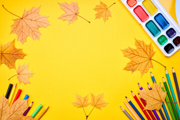 Wall Mural - education and stationery concept. above view for yellow desk. decorated fall leaves and color pencils, markers and other tools. empty space for design