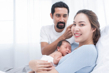 Wall Mural - smiling mother and father holding their newborn baby at home..portrait of happy family at home, young parents holding on hands little sweet newborn baby, love and happiness concept.