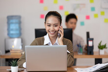 Happy Asian Business Woman Talking With Customer On Mobile Phone To Get Requirement And Sale Support At Modern Office Or Co-Working Space,Startup Small Business Concept