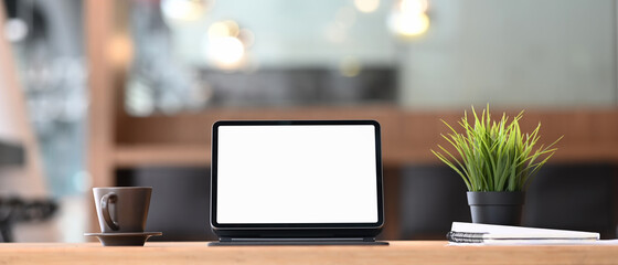 Modern workplace with mockup blank screen desktop of computer tablet and coffee cup on wooden desk.