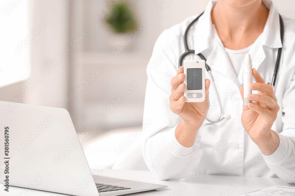 Doctor with digital glucometer and lancet pen in clinic. Diabetes awareness concept